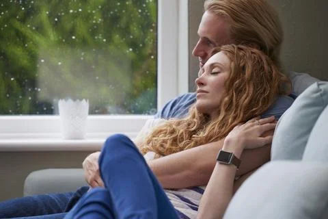 Relax, cuddle and couple with support on couch in home, comfort and security for Stock Photos