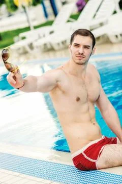 Relax by the pool. a young guy sitting in the pool and looking away through s Stock Photos
