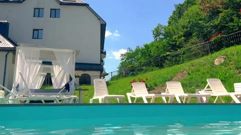 Relaxation area by pool in backyard of house on sunny day. Stock Footage 245787107