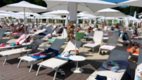 Relaxation area by the pool with plenty of sun loungers and parasols.  動画素材 318971481