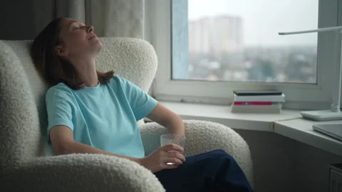 Relaxation techniques for stress relief by the window in a cozy apartment during Stock Footage 322164454