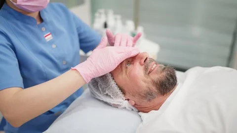 Relaxed bearded man receiving a professional anti-wrinkle facial massage fr.. Stock Footage 345235864