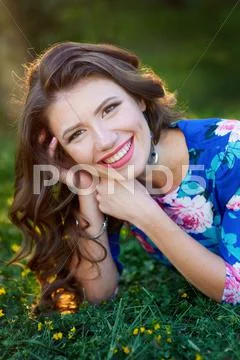 Relaxed beautiful young woman in blue dress lying on grass Stock Photos