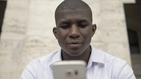 Relaxed black man using smartphone in the city.slow motion Stock Footage 101781344