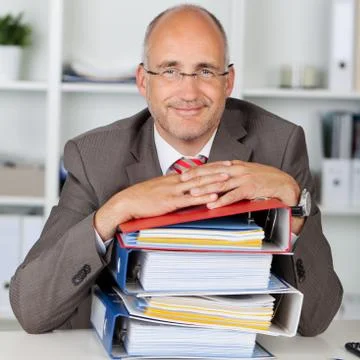 Relaxed businessman with a stack of binders 写真素材