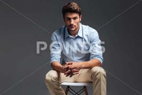 Relaxed casual handsome man in blue shirt sitting on chair Stock Photos