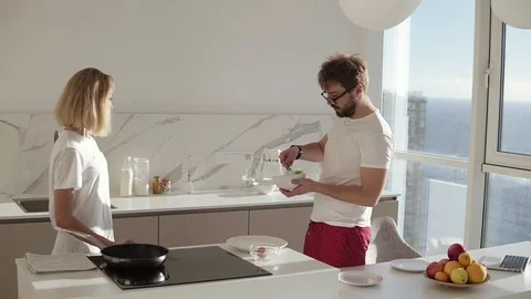 Relaxed caucasian man preparing breakfast for two in kitchen at home and mixing Stock Footage 123467764