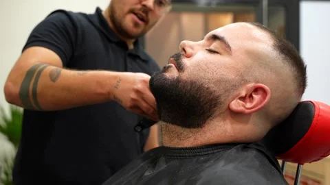 Relaxed client with eyes closed while barber trims beard Stock Footage 320394500