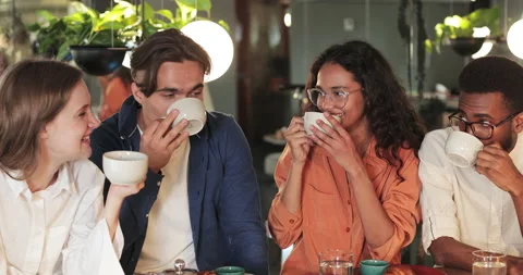 Relaxed colleagues drinking tea, laughing and gesturing while sitting in cosy Stock Footage 135723712