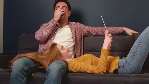 Relaxed couple are lying on the couch with a tablet spending together the Stock Footage 146512857