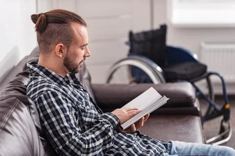 Relaxed disabled man reading on the couch Stock Photos