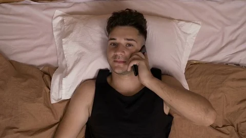 Relaxed guy talking on his smartphone while he is in bed Stock Footage 80177508