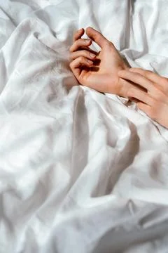 Relaxed Hands On White Bed Sheets In Morning Light Stock Photos