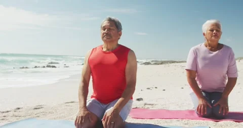 Relaxed hispanic senior couple practicing yoga on mats on beach Stock Footage 335268374