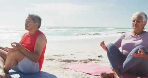 Relaxed hispanic senior couple practicing yoga on mats on beach Stock Footage 336241394