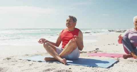 Relaxed hispanic senior couple practicing yoga on mats on beach Stock Footage 343511584