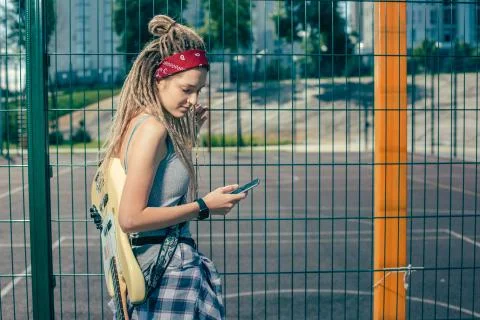 Relaxed lady with dreadlocks looking at the screen of her smartphone Stock Photos