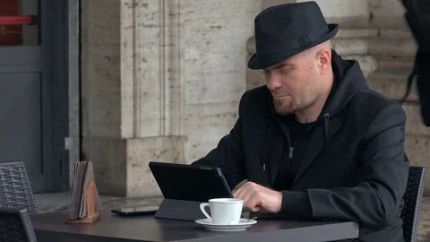 Relaxed man with  black hat  typing on tablet and smiles Stock-Footage 74703963