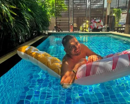 Relaxed man floating with inflatable circle in swimming pool and enjoy nature Stock Photos