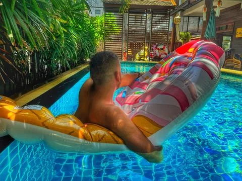 Relaxed man floating with inflatable circle in swimming pool Stock Photos