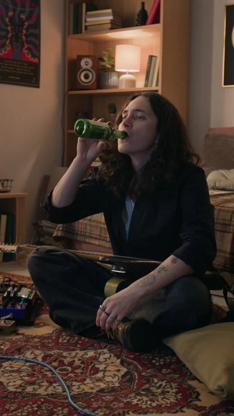Relaxed Man with Guitar Sitting on Floor Drinking Beer Stock Footage 338076064