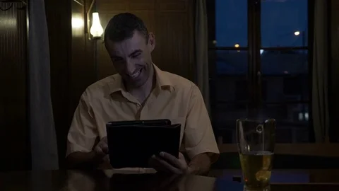 Relaxed man having a beer and laughing and chatting on social media at bar Stock Footage 81722492
