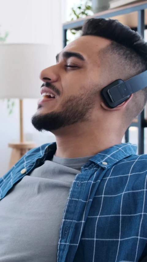 Relaxed man in headphones smiling while listening to music at home. Video stock 326639878