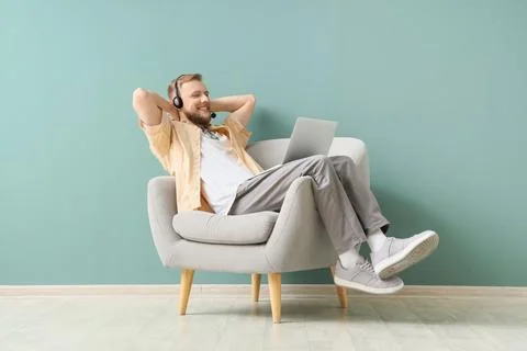 Relaxed man in headset using laptop for remote work or online learning, leani Stock Photos