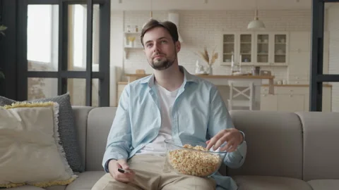Relaxed Man Holding Remote And Popcorn While Watching Television At Home 스톡 동영상 331788797