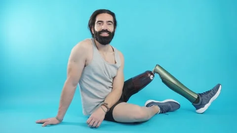 Relaxed man with a leg prosthesis sitting on the floor Video stock 228011346