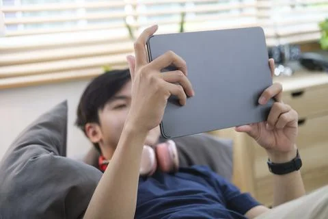 Relaxed man lying on comfortable couch and surfing internet with digital ta.. Stock Photos