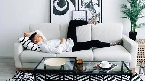 Relaxed man lying on couch Stock Photos