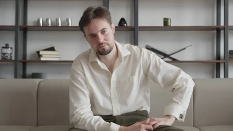 Relaxed Man Resting On Sofa Then Looking At Camera In Modern Home Interior Stock-Footage 331788645