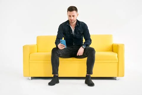 Relaxed man sitting on couch using hsi mobile phone Stock Photos