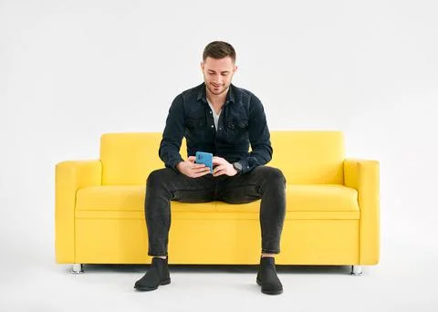 Relaxed man sitting on couch using hsi mobile smart phone 스톡 사진