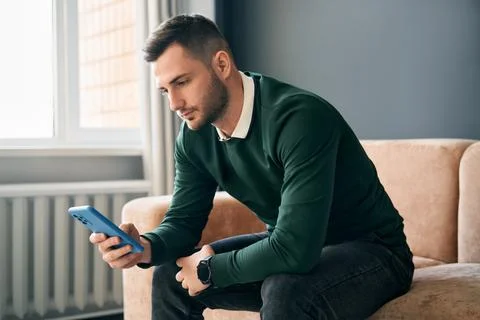 Relaxed man sitting on couch using hsi mobile smart phone Stock Photos
