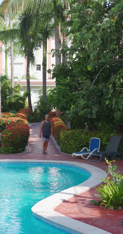 Relaxed man walking poolside at hotel in tropical environment. Stock Footage 249633395