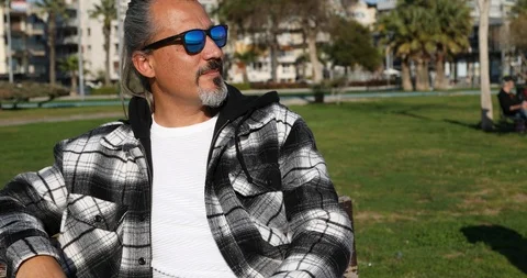 Relaxed middle aged man sitting on a park bench 2 Stock Footage 126197572
