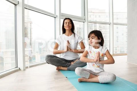 Relaxed people woman and kid practicing yoga indoor, sitting legs crossed on Stock Photos