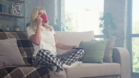 Relaxed positive lady sit couch drink coffee watch tv movie Stock Footage 166904941