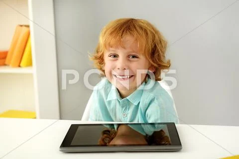 Relaxed redhead pupil sitting with tablet Stock Photos