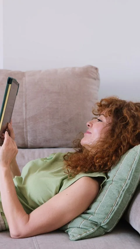 Relaxed redhead woman using a tablet lying on the sofa Stock-Footage 343509430