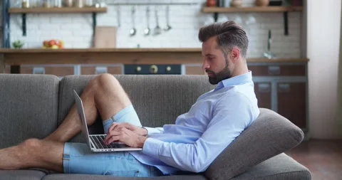 Relaxed serious freelancer using laptop device leaning on sofa at home office Stock Footage 160804272