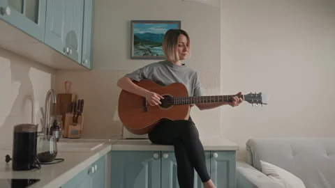 Relaxed singersongwriter practicing in cozy kitchen setting. An intimate scene Stock Footage 342065769