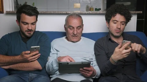 Relaxed, smiling sons and old father using tablet and smartphone on sofa Stock-Footage 76316466