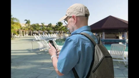 Relaxed Traveler With Backpack Using Phone At Poolside Resort On Vacation Stock Footage 329906238