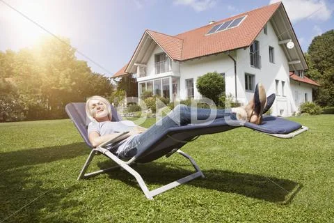 Relaxed woman in deck chair in garden Stock-Fotos