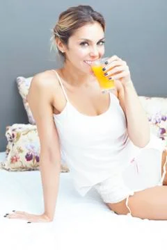 Relaxed woman drinking orange juice at home in bedroom Stock Photos