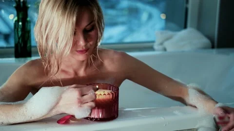 Relaxed woman lighting a candle while taking a bubble bath in the evening. Stock Footage 171645703