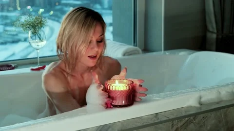 Relaxed woman lighting a candle while taking a bubble bath in the evening. Stock Footage 171783863